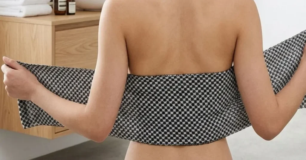 Femme se frottant le dos seule avec une serviette exfoliante — nettoyer son dos sans aide